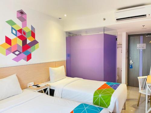 Habitación con 2 camas y una pintura en la pared. en Dafam Express Jaksa Jakarta, en Yakarta