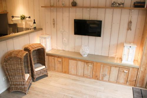 a room with two wicker chairs and a flat screen tv at Vakantiewoning Weverijstraat met strandcabine in Domburg