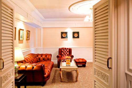 a living room with leather furniture and a table at Royal Princess Larn Luang - SHA Extra Plus in Bangkok