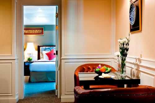 a room with a chair and a table and a bed at Royal Princess Larn Luang - SHA Extra Plus in Bangkok