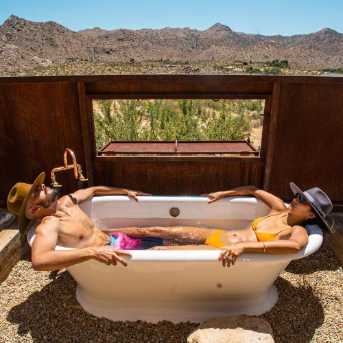 two people laying in a bath tub in the desert at Sacred Sands in Joshua Tree