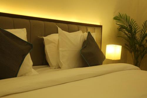 a bedroom with a bed with pillows and a lamp at PARK IRIS HOTELS, Bharathi Nagar in Vijayawāda