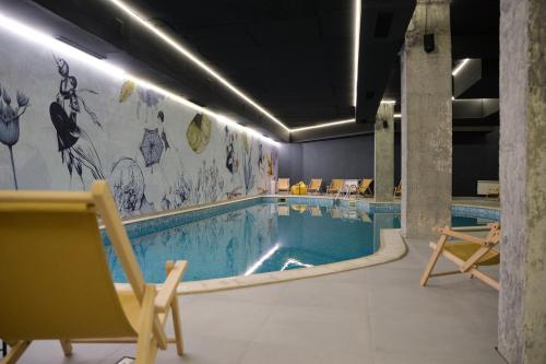 a swimming pool in a room with chairs and a pool at Flora Hotel - Apartments in Borovets