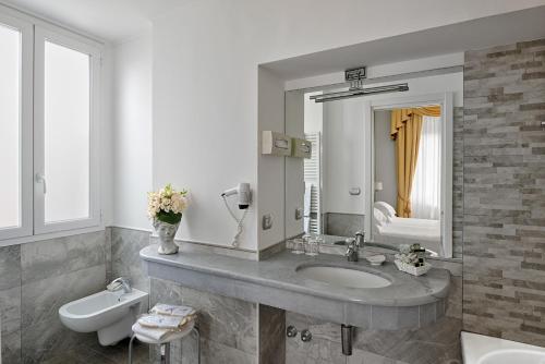 a bathroom with a sink and a toilet and a mirror at Hotel Paradiso in Sanremo
