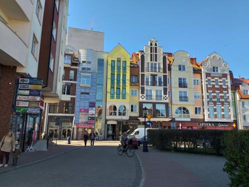 a city street with buildings and people walking on the street at Apartament na nowej starówce in Kołobrzeg