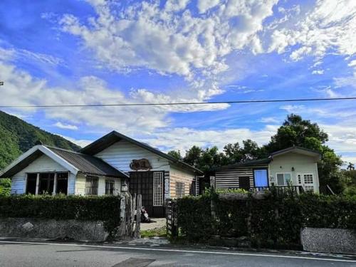 a white house with a fence in front of a house at Taroko Railway Authentic B&B in Xiulin