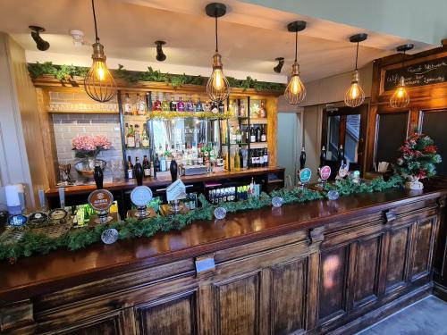 a bar with a long wooden counter top with bottles at The Gateway Hotel in Kendal