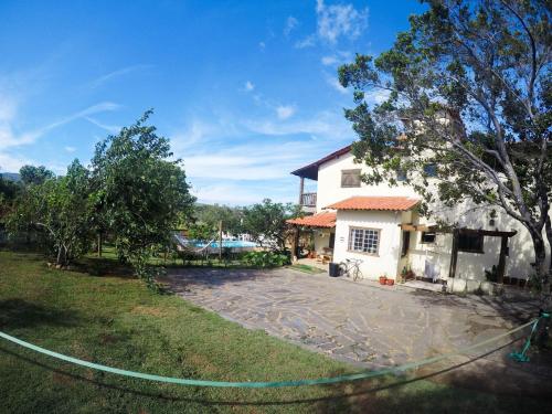a house with a hose in front of a yard at Topo do Cipó Ecopousada Vegana in Serra do Cipo