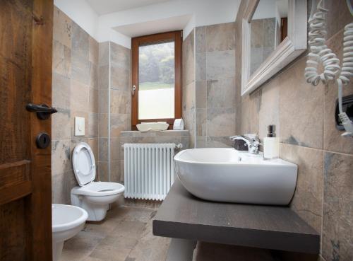 a bathroom with a toilet, sink and tub at Agriturismo Le Radici in San Fedele Intelvi
