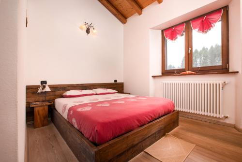 a bedroom with a bed with red sheets and a window at Agriturismo Le Radici in San Fedele Intelvi