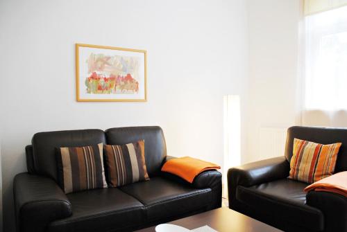 a living room with a leather couch and a chair at Appartementanlage-Ferienwohnungen Weiße Möwe in Sassnitz