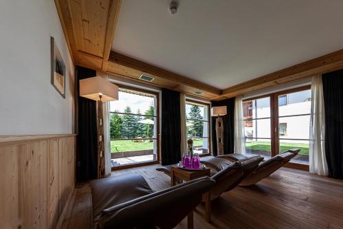 a living room with a leather couch and a table at Villa Flora Mountain Lodges in San Cassiano