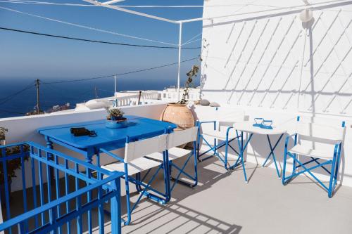 einen Balkon mit blauen Tischen und Stühlen auf einem Schiff in der Unterkunft Boreas Stone House in Anafi