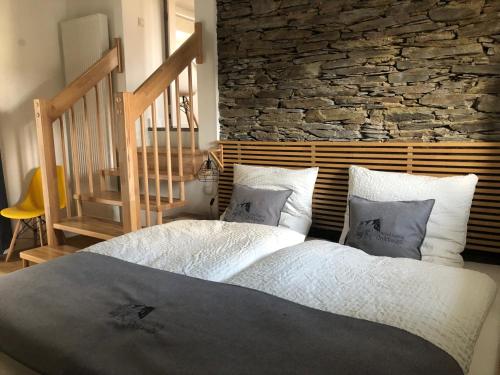 um quarto com uma cama grande e uma parede de pedra em Hübingen Cottage em Hübingen