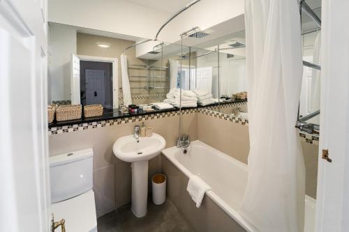 a bathroom with a sink and a tub and a toilet at Park Lane Apartments Crawford Place in London