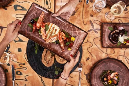 a person holding a plate of food on a table at Calilo in Manganari