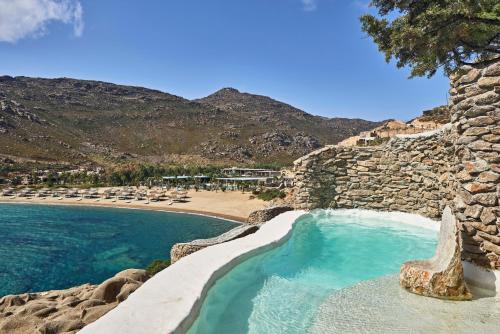 a swimming pool next to a beach with a rock wall at Calilo in Manganari