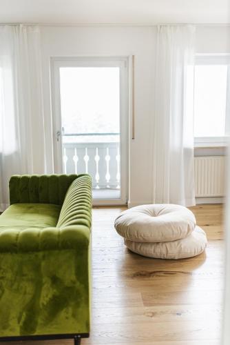 a living room with a green couch and a large window at Zauberhaft im Naturpark Altmühltal in Greding