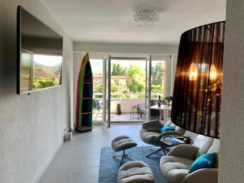 a living room with a couch and chairs and a surfboard at Bijou Lido Golf Ascona in Ascona