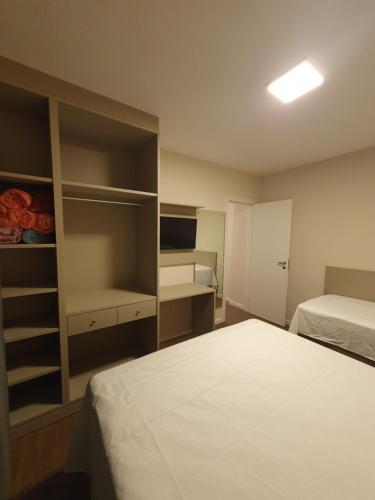 una camera d'albergo con letto, TV e scaffali di Apartamento Pé na Areia, Beira Mar, Balneário Camboriú a Balneário Camboriú