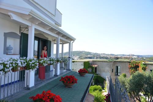Eine Frau steht auf dem Balkon eines Hauses mit Blumen. in der Unterkunft b&b Dea Fortuna in Bacoli