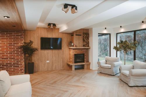 a living room with white furniture and a fireplace at Vila Casa din gradina in Voivodeni