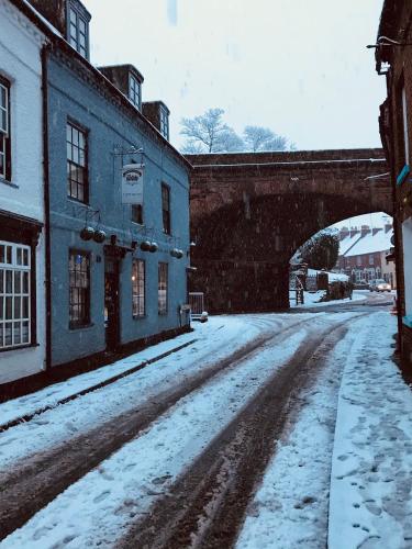 a snow covered street with a bridge in the background at Severn Valley Guest House in Bewdley