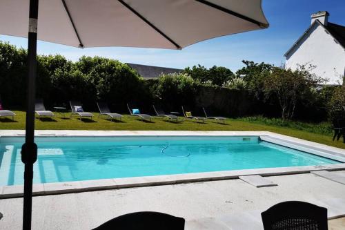 une piscine avec des chaises et un parasol dans l'établissement Maison de famille Penmarch, à Penmarcʼh
