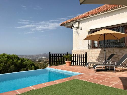 a house with a swimming pool and an umbrella at Villa FenaVista in Mijas