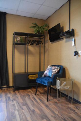 a living room with a blue chair and a tv at Hotel Restaurant Cafe Houben in Nunhem