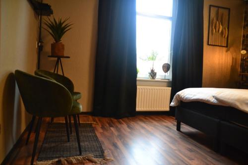 a bedroom with a bed and a chair and a window at Hotel Restaurant Cafe Houben in Nunhem