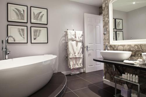 a bathroom with a bathtub, sink, and mirror at Longueville Manor in Saint Helier Jersey