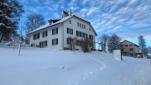 a white house in the snow in the snow at Jurabelle in La Côte-aux-Fées