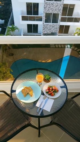 a glass table with two plates of food on a balcony at Tropical Beach Bayahibe in Bayahibe