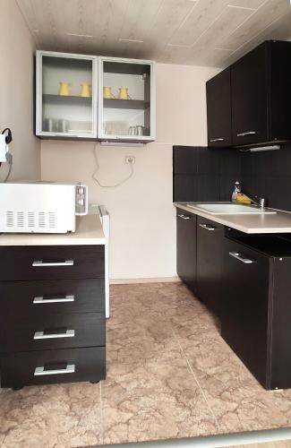 a kitchen with black cabinets and a sink at Sineva Guest House in Ravda