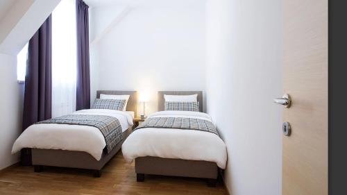 two twin beds in a room with two windows at Apartman Davidović in Brzeće