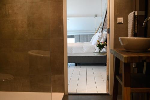 a bathroom with a sink and a bedroom with a bed at Loft in de Polder (L) in Grootschermer