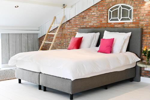 een slaapkamer met een groot bed met roze kussens bij Loft in de Polder (L) in Grootschermer