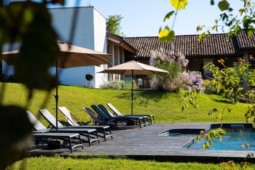 una terrazza con sedie e ombrellone accanto alla piscina di ROSTAGNI1834: VILLA WITH 2 APTS AND POOL IN THE BAROLO REGION a Novello
