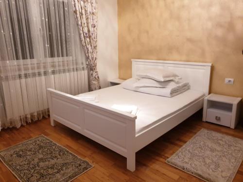 a white bed in a room with a window at Pensiunea Putnisoara in Putnişoara