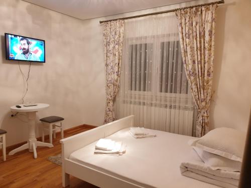 a room with a bed and a tv on the wall at Pensiunea Putnisoara in Putnişoara