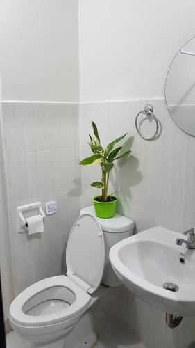 La salle de bains est pourvue de toilettes, d'un lavabo et d'une plante en pot. dans l'établissement Keys 'N Places Holiday Rentals at Mesaverte Condo, à Cagayán de Oro