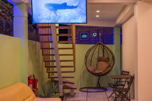 a room with a hanging hammock and a tv at Turtle Maldives - Your Gateway to the Beach & Marine Adventures Await! in Omadhoo