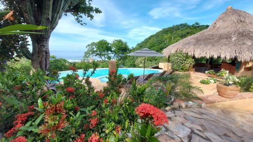a garden with a swimming pool and a grass umbrella at OceanoMar in Mazunte