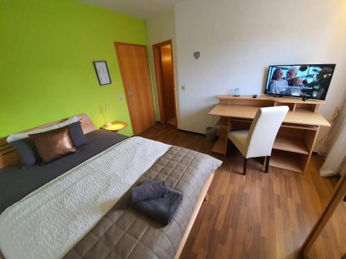 a bedroom with a bed and a desk with a computer at Pension Reinhardshäusle in Reinhardshausen