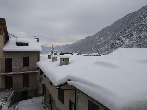 a snow covered roofs of buildings with mountains in the background at Appartamento la Torre Vinadio in Vinadio