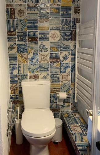 a toilet in a bathroom with blue and white tiles at Casa do Xão 2 in Serpa