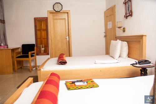 a hotel room with two beds and a clock on the wall at Asantewaa Premier Hotel in Kumasi