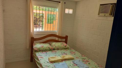 a small bedroom with a bed with a window at Casa de praia in Porto De Galinhas