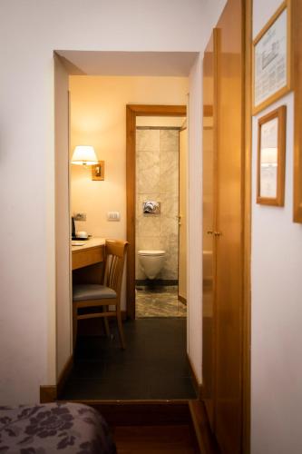 a room with a bathroom with a toilet and a desk at Hotel Giolli Nazionale in Rome